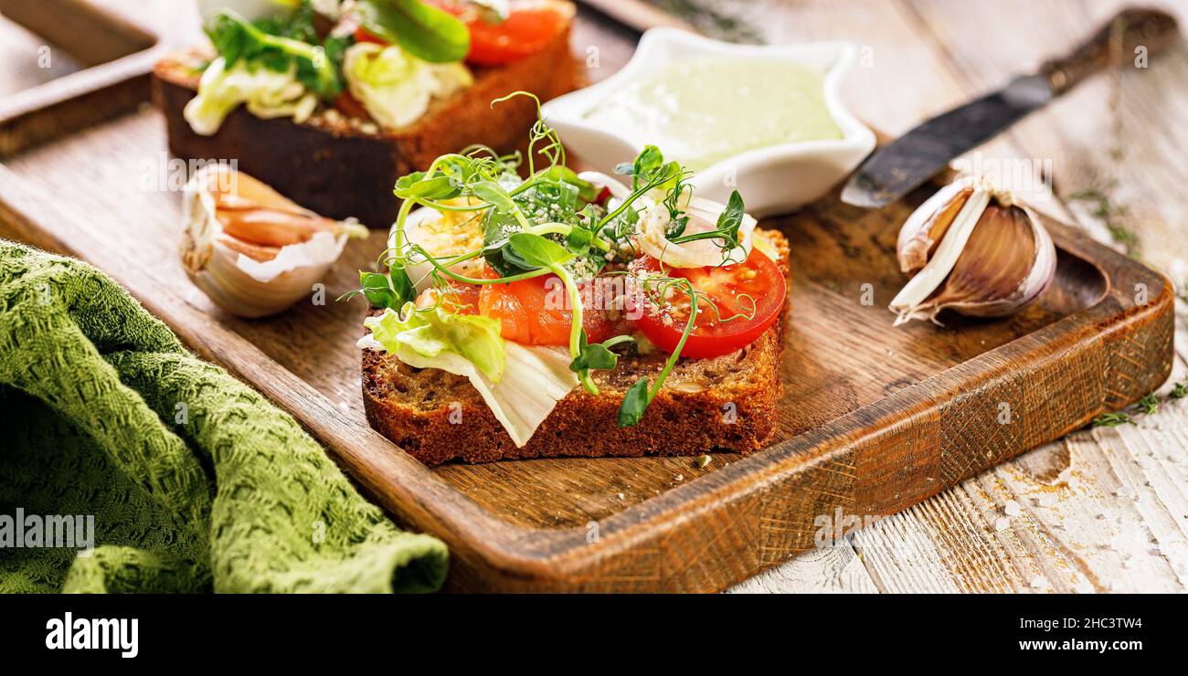 Striscione per alimenti. Brinda con pesce salato, formaggio, uova, anelli di cipolla e insalata. Stuzzichini o sandwich appetitosi con salmone affumicato. Colazione tradizionale Foto Stock