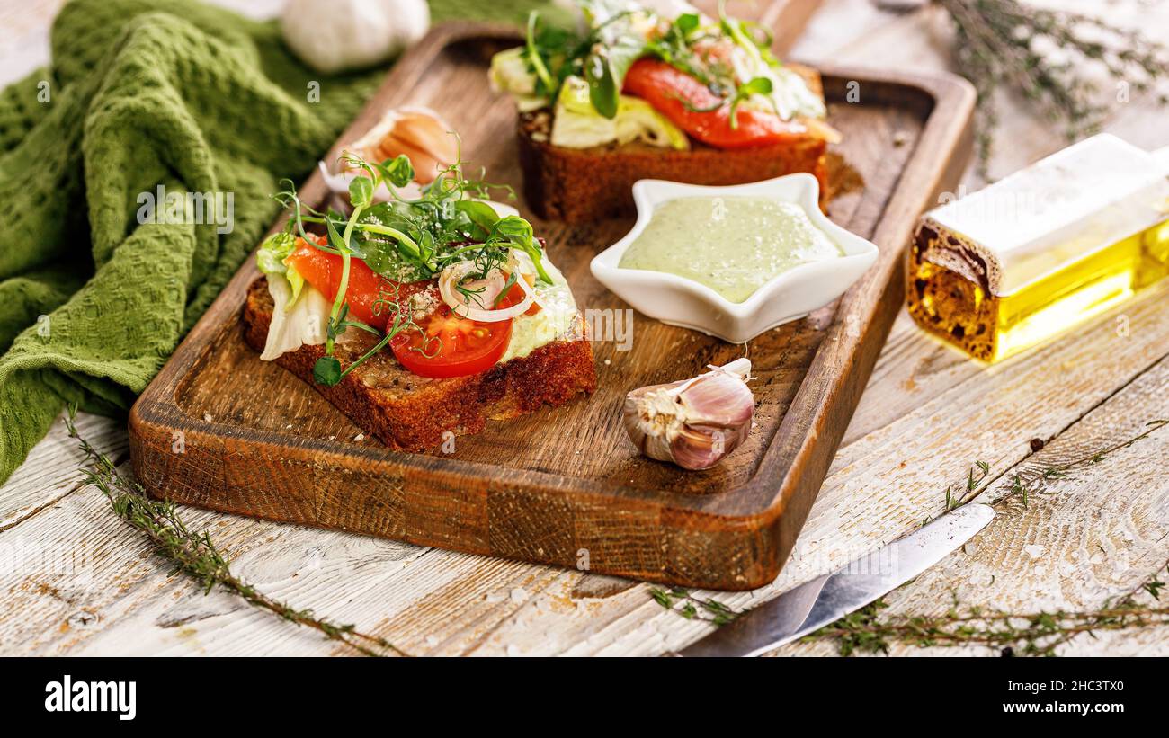 Striscione per alimenti. Stuzzichini o sandwich appetitosi con salmone salato. Brinda con pesce affumicato, formaggio morbido, uova, anelli di cipolla e insalata fresca. Foto Stock