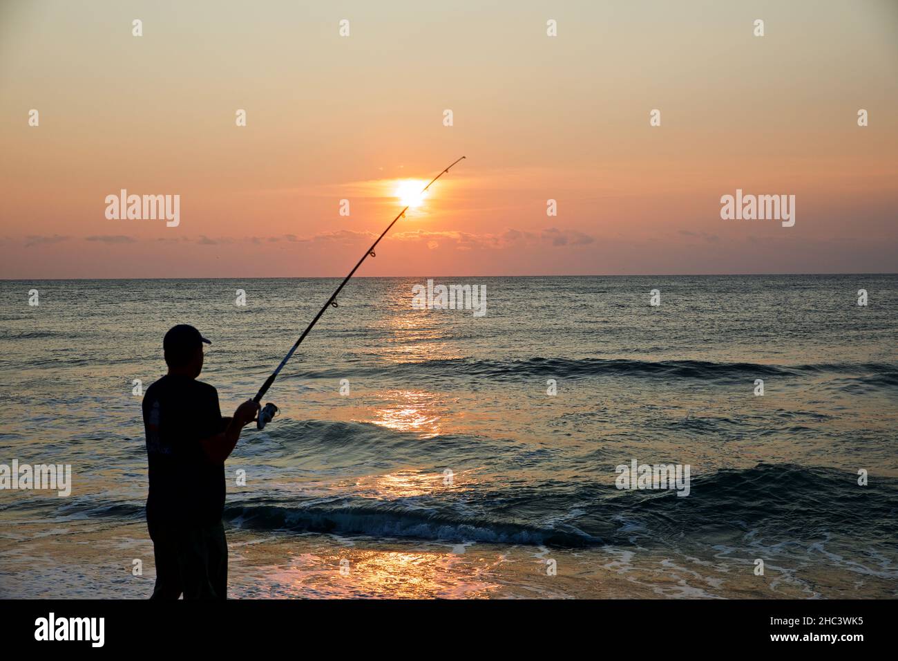 Silhouette di una persona che pesca in spiaggia Foto Stock