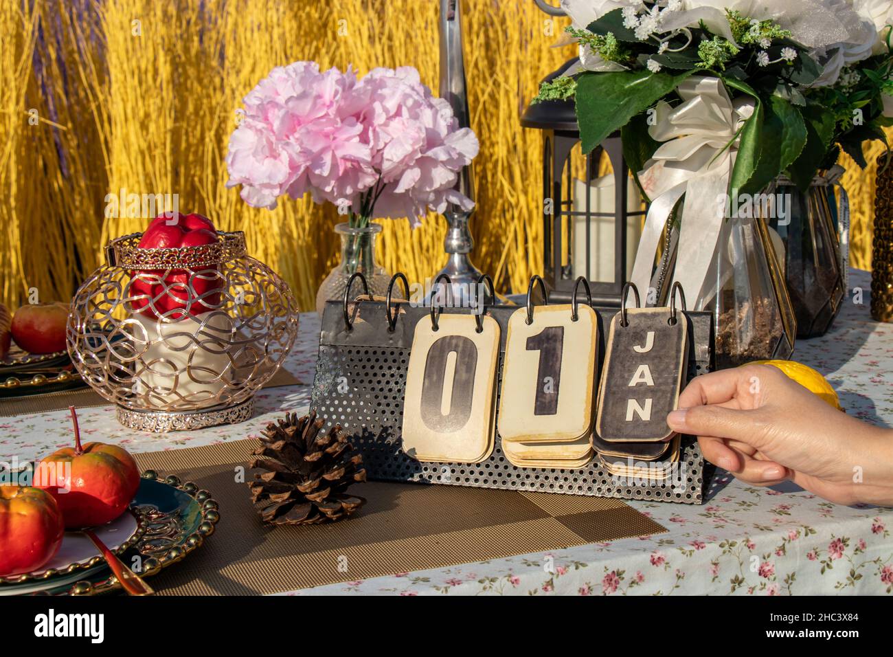 Mano girando pagina su flip vintage calendario metallo cambiare a 1 gennaio, sul tavolo con decorazione partito. Conto alla rovescia per nuovo anno concetto Foto Stock