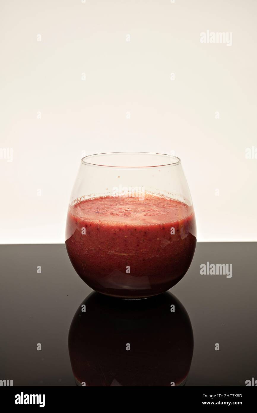 Shot verticale di un bicchiere di frullato di frutta su un tavolo Foto Stock