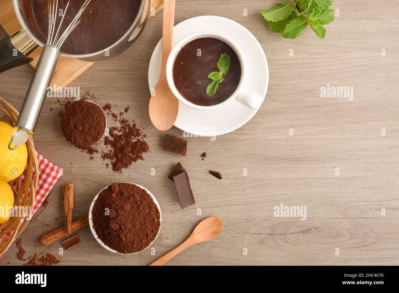 Preparazione della ricetta al cioccolato caldo con menta, limone e cannella sul tavolo da cucina. Vista dall'alto. Foto Stock