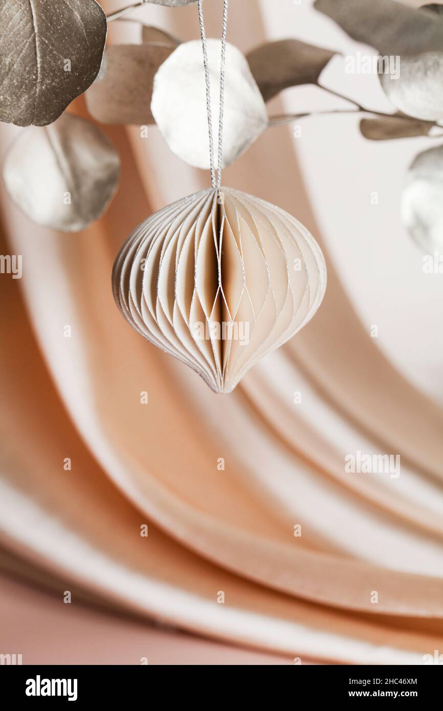 Decorazioni natalizie in carta a nido d'ape su ramo dorato su sfondo beige con tessuti. Vacanze stagionali, biglietto d'auguri, vacanza ecologica. Foto Stock