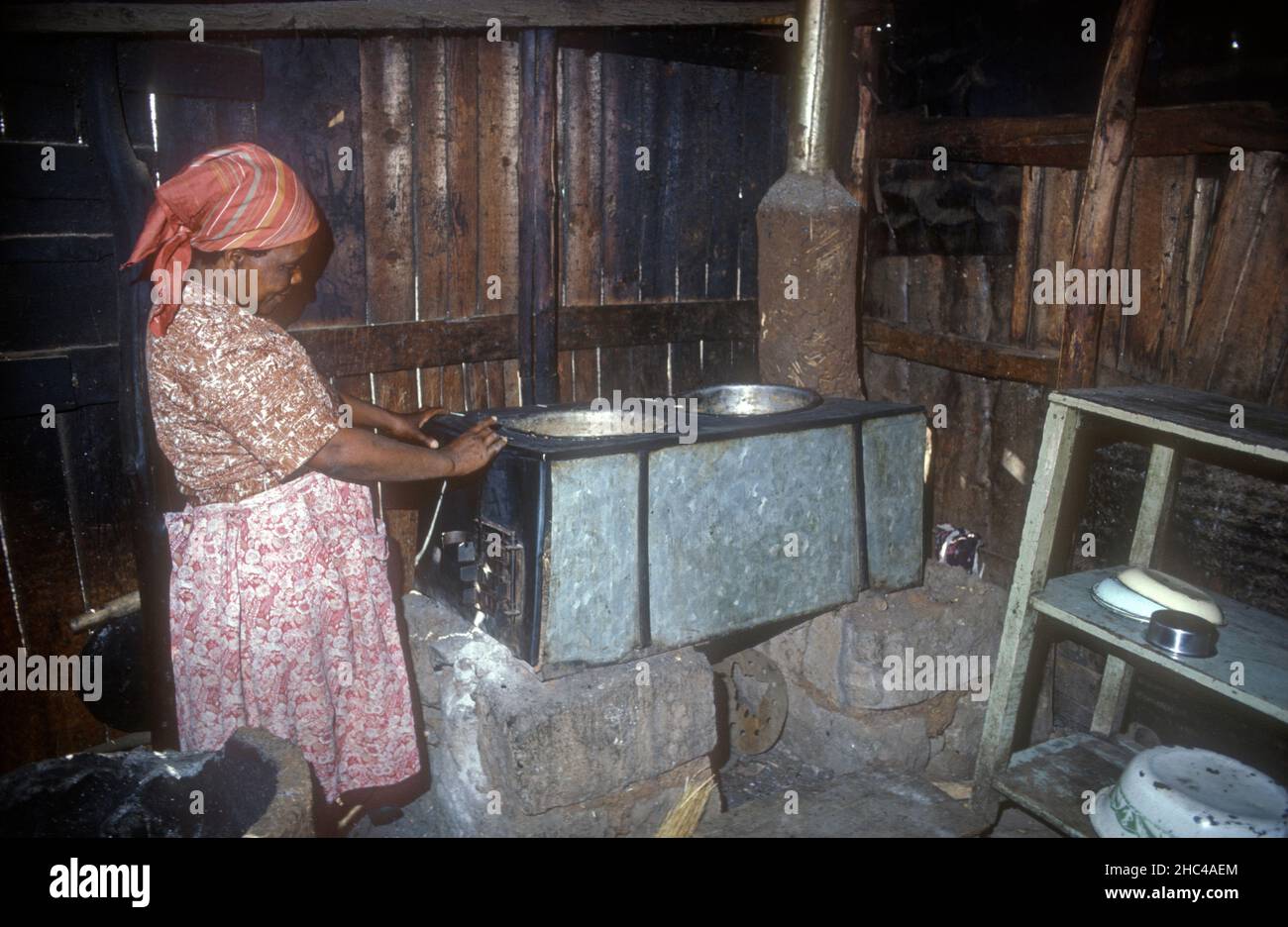 donna keniana che cucina su Bellerive combustibile efficiente metallo placcato stufa a legna , Kenya Africa orientale Foto Stock