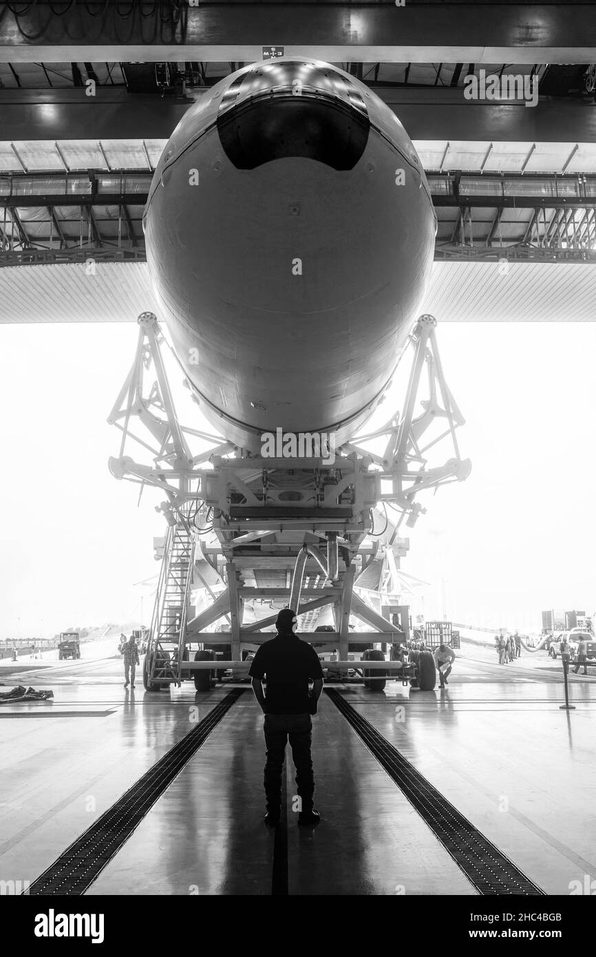 L'ingegnere spaziale guarda un veicolo spaziale costruito. Razzo con veicolo spaziale, rotola fuori dall'hangar. Spazio di lancio preparazione. Razzo, all'interno della manutenzione Foto Stock