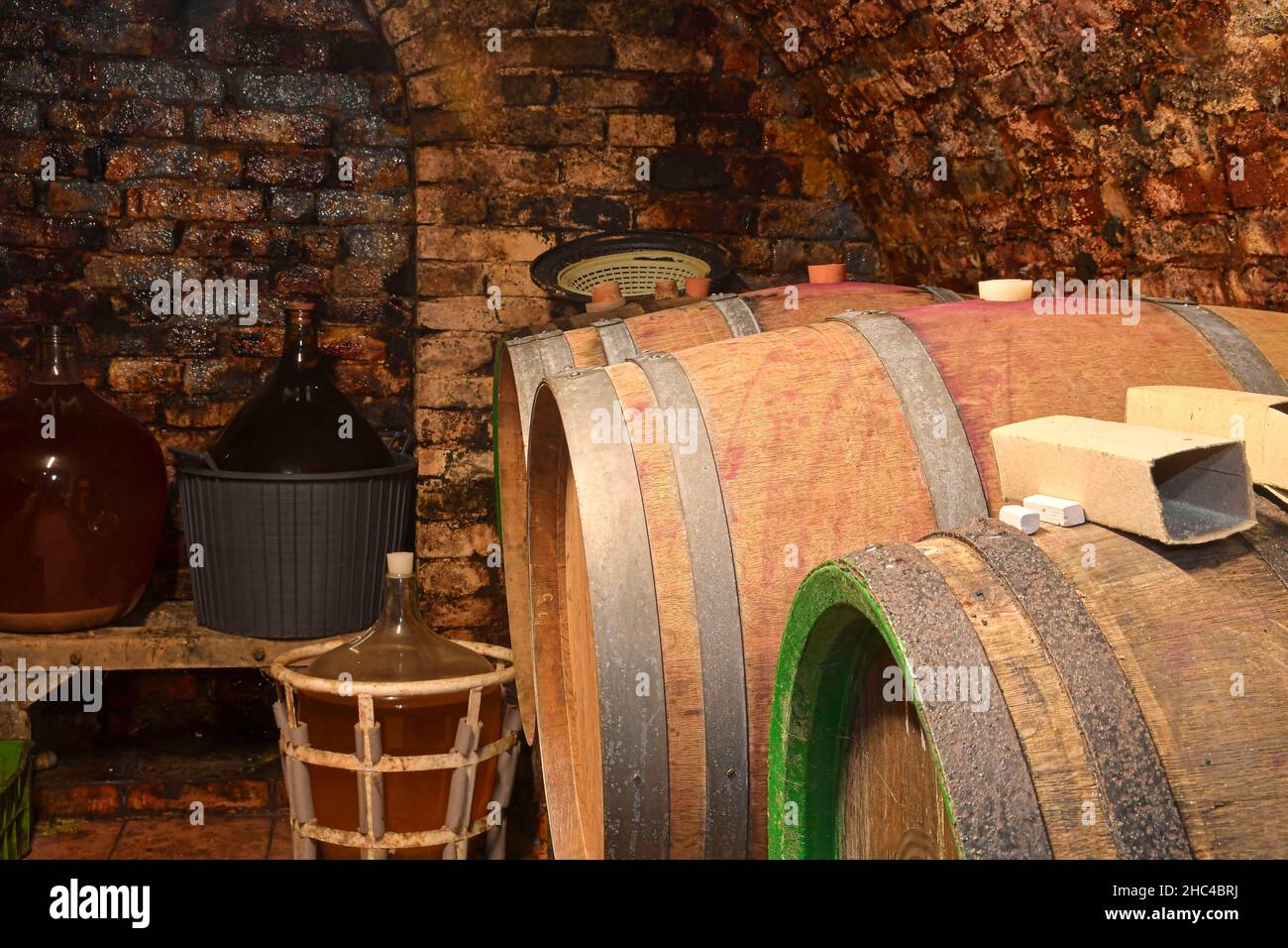Vecchia cantina con demijohns e botti di legno. Produzione tradizionale del vino Foto Stock