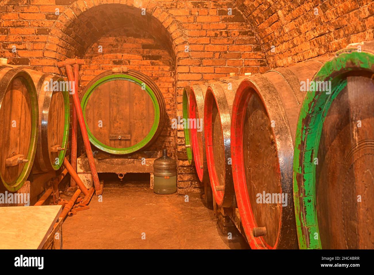 Vecchia cantina con bottiglie e barili sotto il castello di produzione del vino Foto Stock