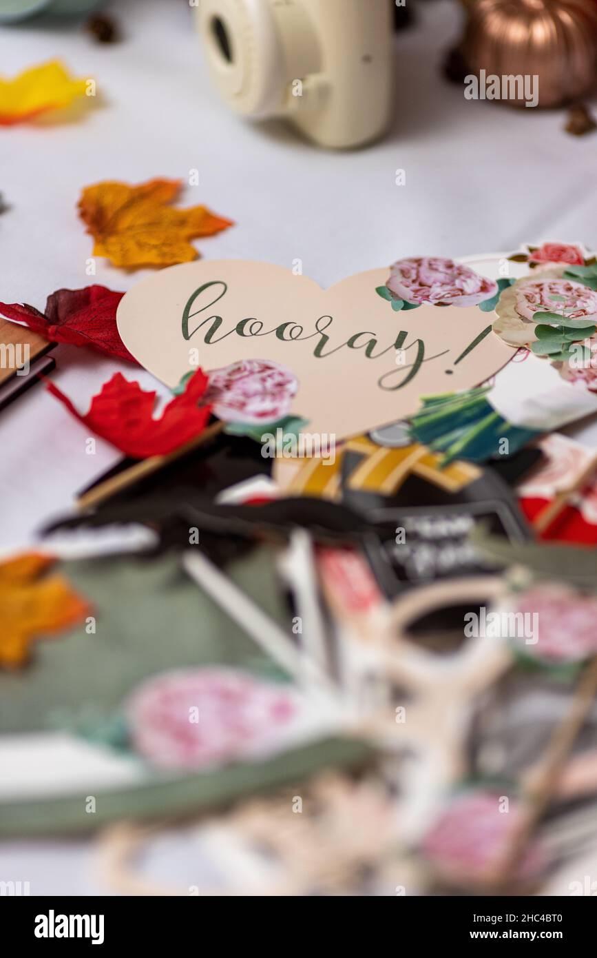 Colpo verticale di foglie autunnali, pezzi di carta e un segno di cuore hooray su un tavolo Foto Stock