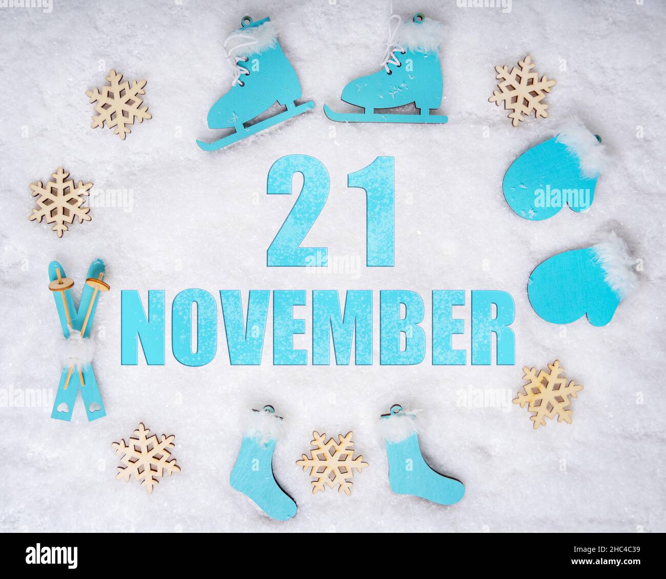 Novembre 21st. Set sportivo con pattini in legno blu, sci, slitte e fiocchi di neve e una data di calendario. Giorno 21 del mese. Concetto di sport invernali. Inverno Foto Stock