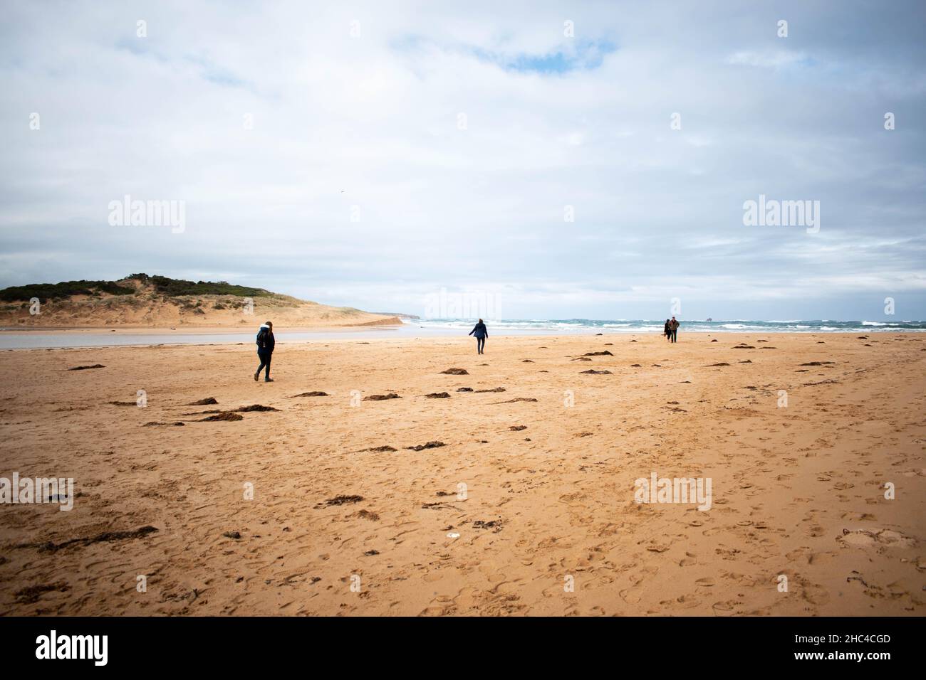 Gruppo di persone che camminano su una spiaggia sotto un bel cielo nuvoloso Foto Stock