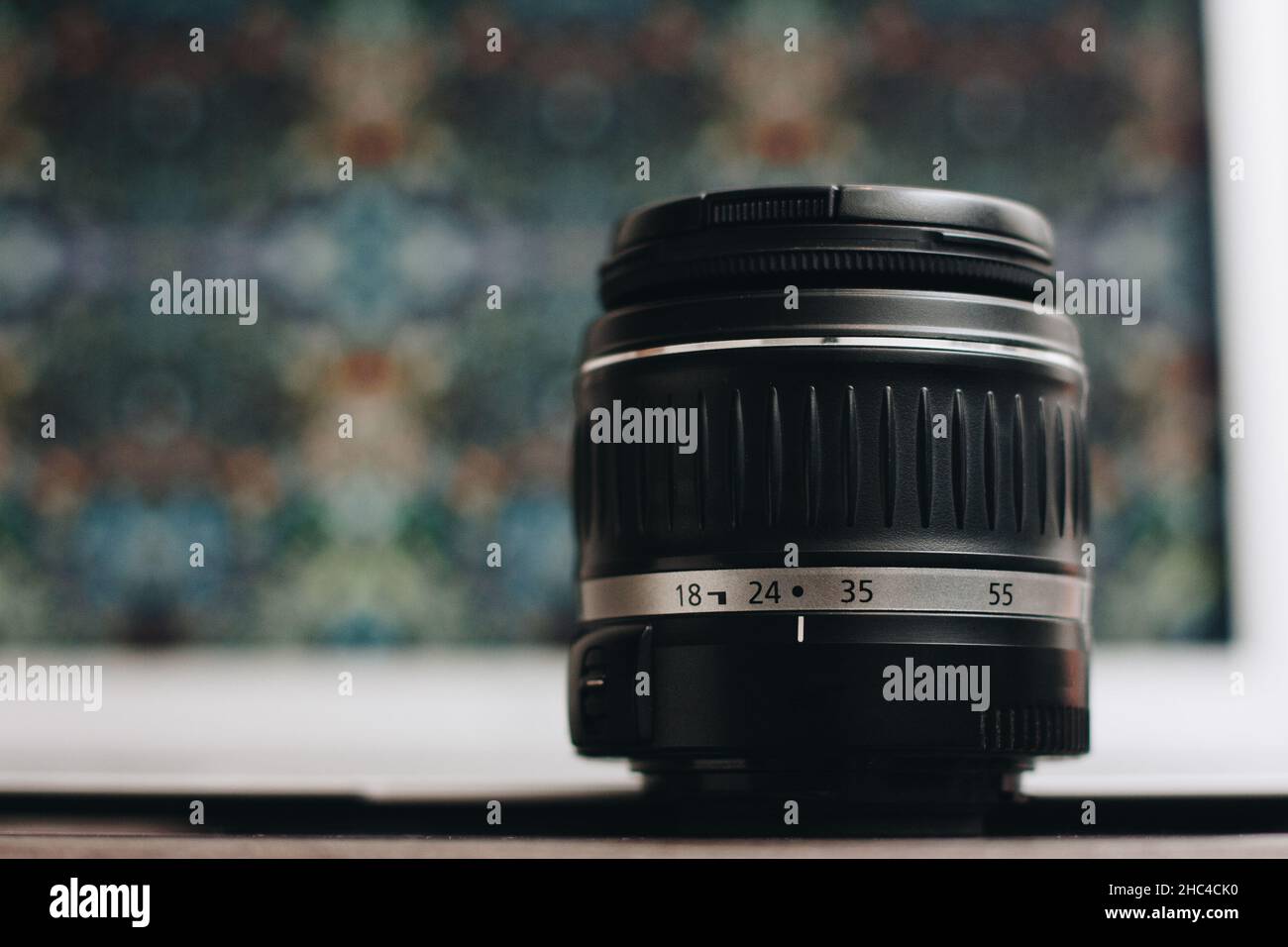 Primo piano di un obiettivo fotografico con sfondo bokeh sul tavolo. Foto Stock