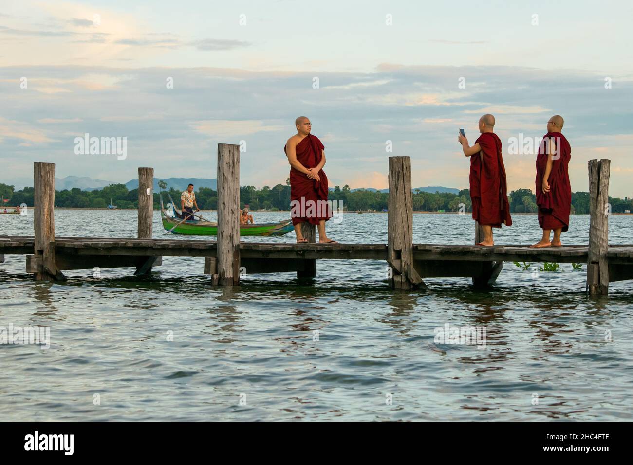 Monaci buddisti che camminano sul ponte U-Bein, durante il tramonto, nel lago di Taungthaman vicino Amarapura, vicino alla città di Mandalay in Myanmar, Birmania, se Asia Foto Stock