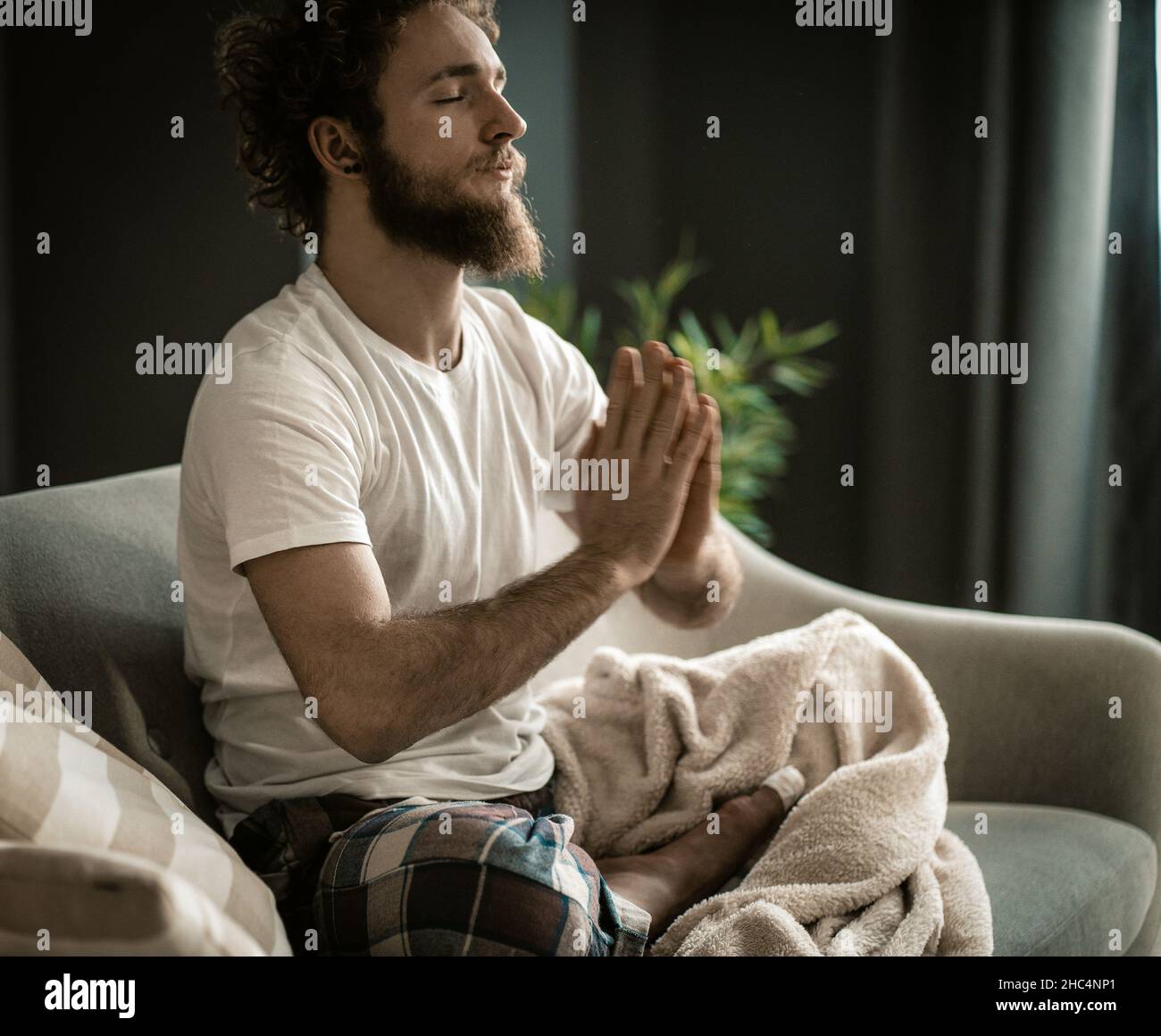 Un uomo forte a Pajamas ha la sua meditazione. Meditazione abituale all'inizio della giornata. Primo piano. Foto di alta qualità Foto Stock