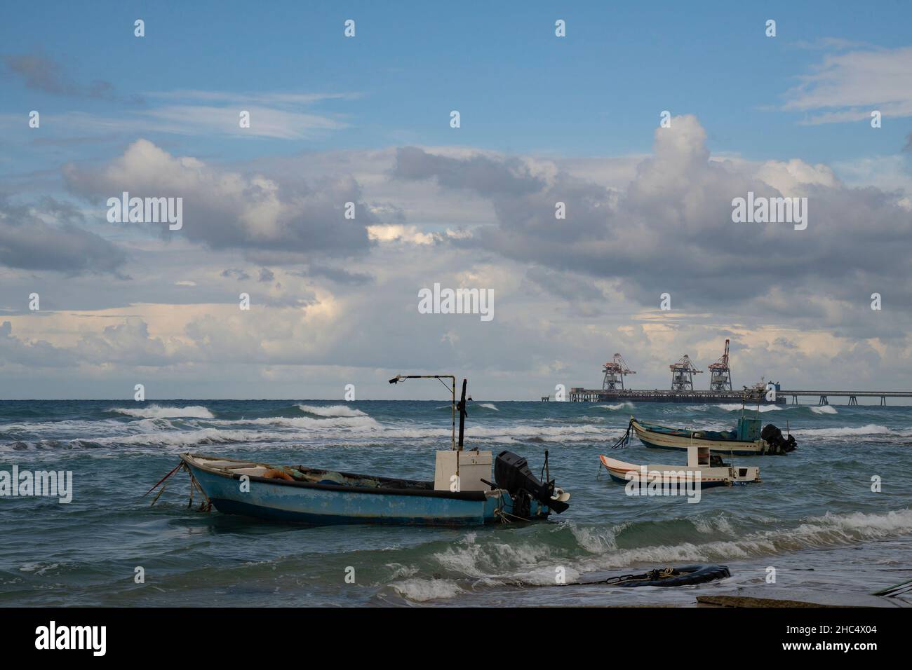 Tre piccole barche da pesca ancorate accanto ad un molo in una nuvolosa giornata invernale. Foto Stock