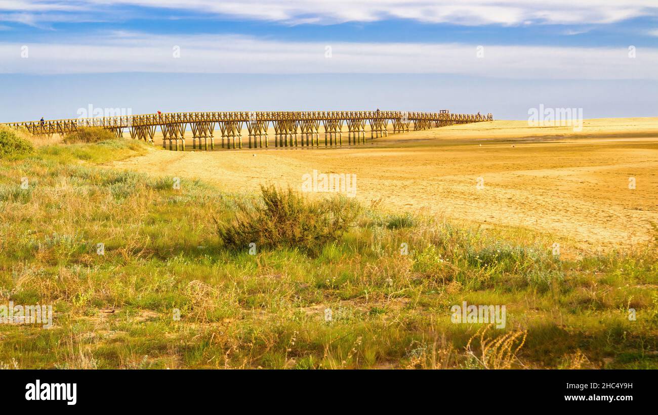 Vista sul ponte di legno che consente l'accesso alla spiaggia quando è in mare. Isla Cristina, Andalusia, Spagna Foto Stock