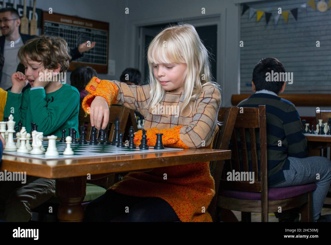 Giochi intelligenti. Un bambino gioca a scacchi, una ragazza e una scacchiera. Strategia. Pensiero logico. La bambina gioca a scacchi Foto Stock