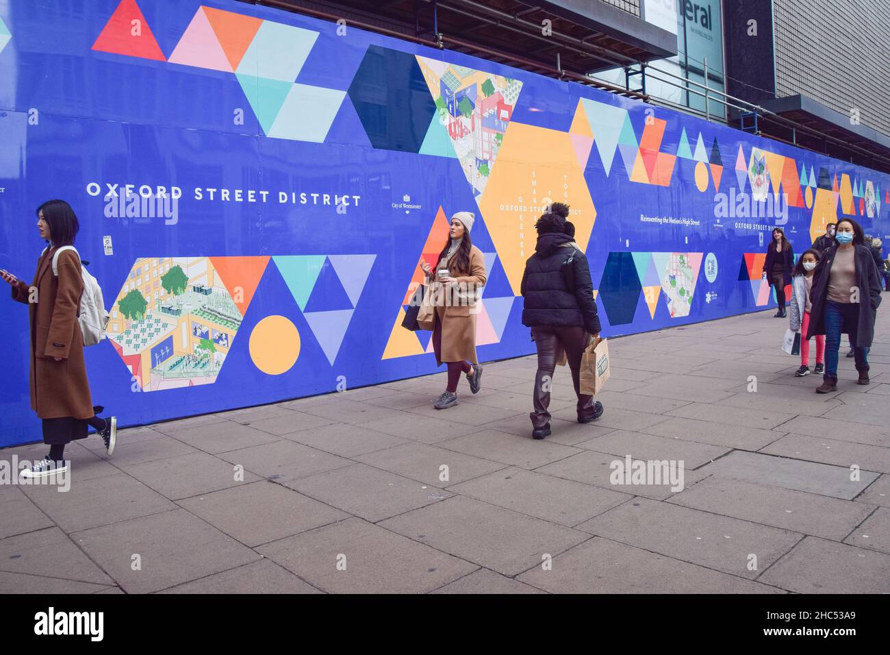 La gente cammina davanti all'ex sito di ristrutturazione del negozio di punta di Debenham in Oxford Street. Londra, Regno Unito 24 dicembre 2021. Foto Stock