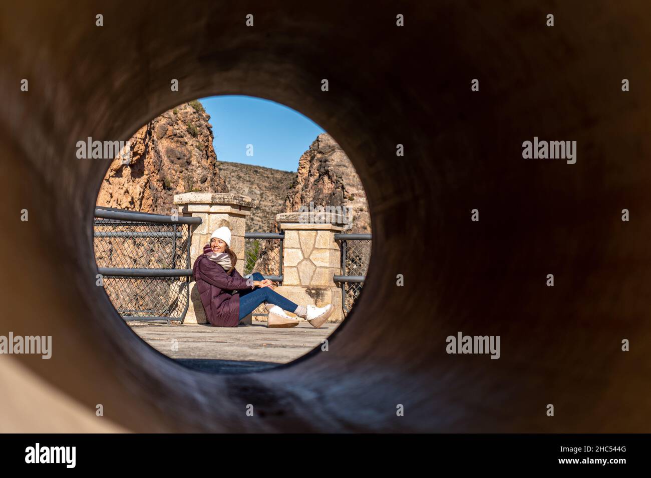 Giovane donna seduta a terra in autunno nella foto scattata attraverso un tubo Foto Stock