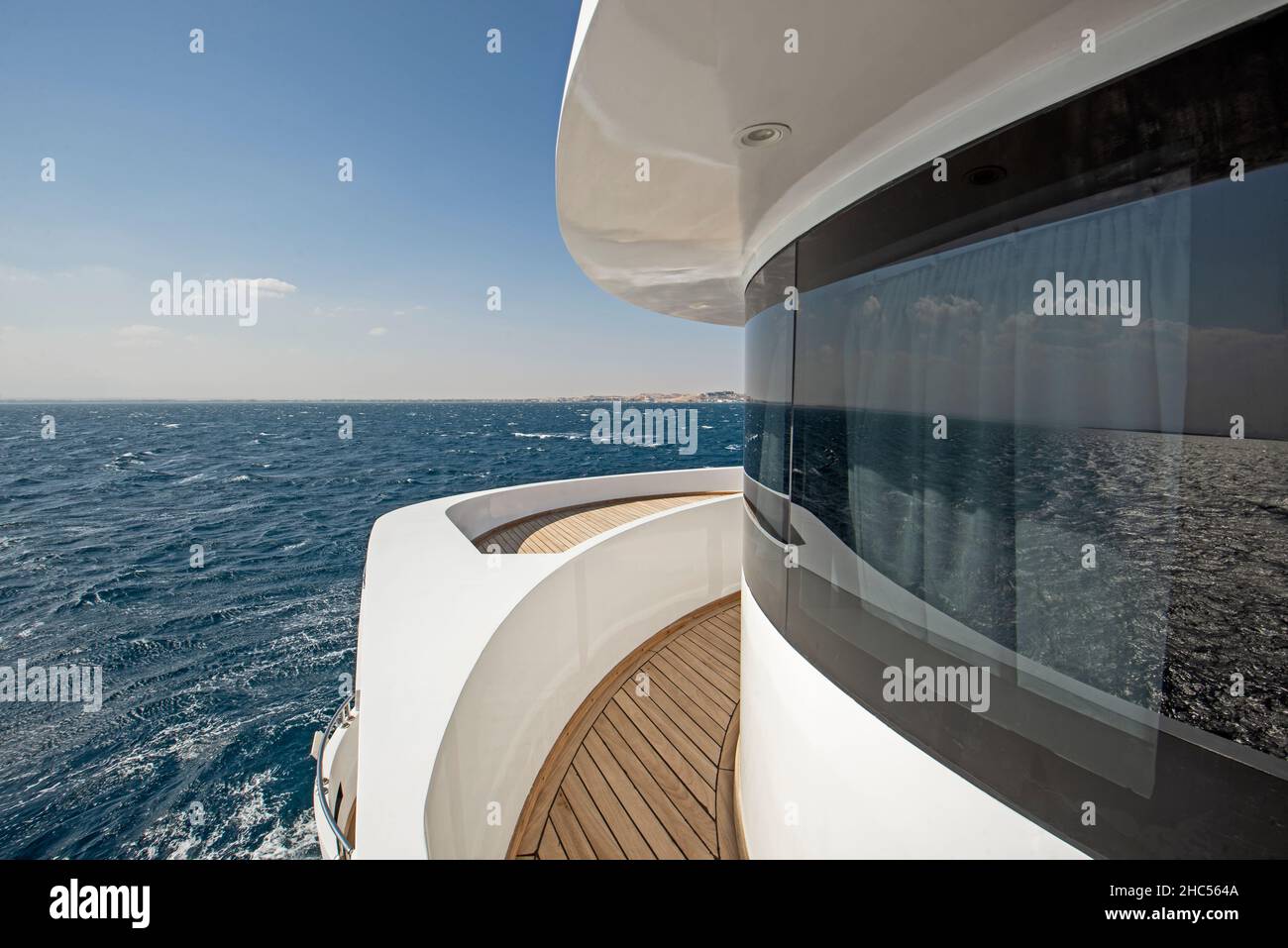 Vista dal ponte di prua in teak di un grande yacht a motore di lusso con sfondo tropicale vista mare Foto Stock