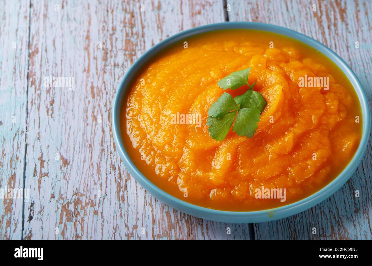 Una ciotola di zuppa di zucca su un tavolo di legno blu Foto Stock