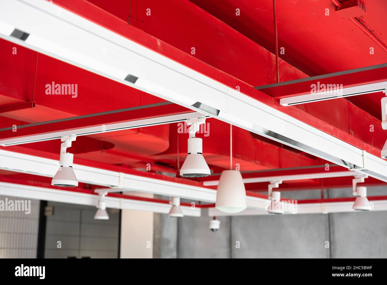 Unità di climatizzazione a cassetta montate a soffitto con altre parti del sistema di ventilazione (tubi, cavi e sfiati) situate all'interno della sala commerciale con Foto Stock