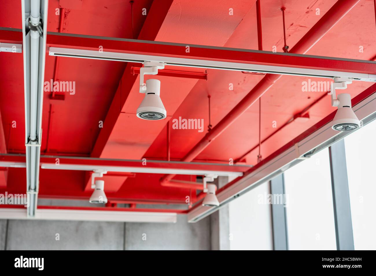 Unità di climatizzazione a cassetta montate a soffitto con altre parti del sistema di ventilazione (tubi, cavi e sfiati) situate all'interno della sala commerciale con Foto Stock