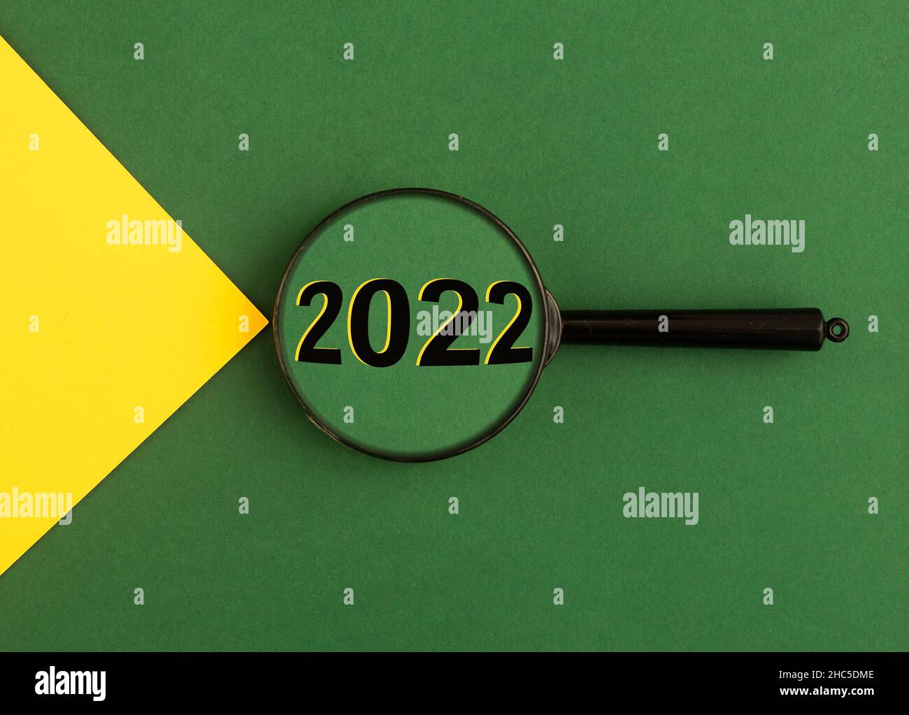 2022 anni attraverso lente di ingrandimento su sfondo verde con fascio di luce giallo. Foto Stock