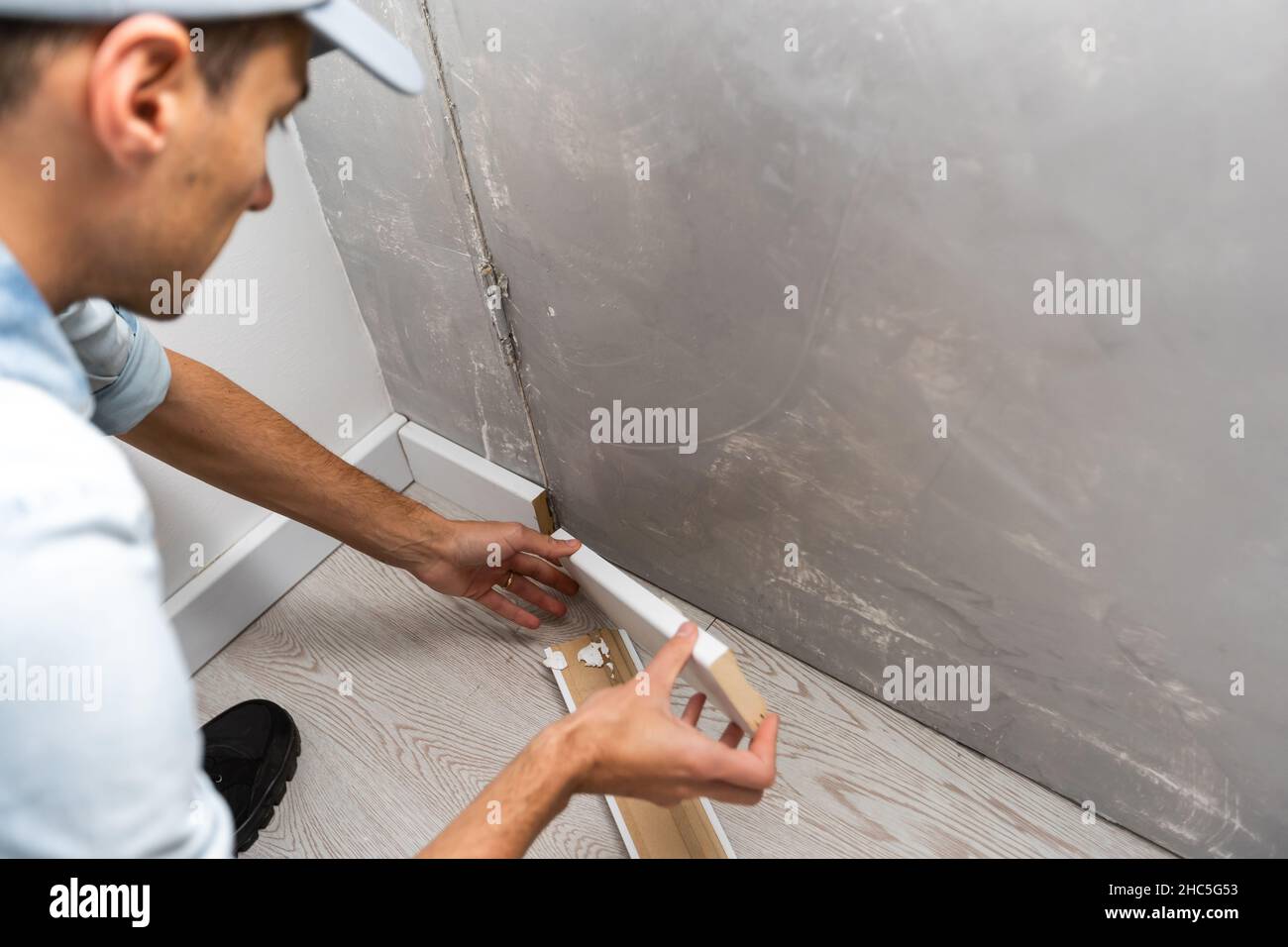 Installazione del nuovo battiscopa dopo la sostituzione del parquet Foto Stock