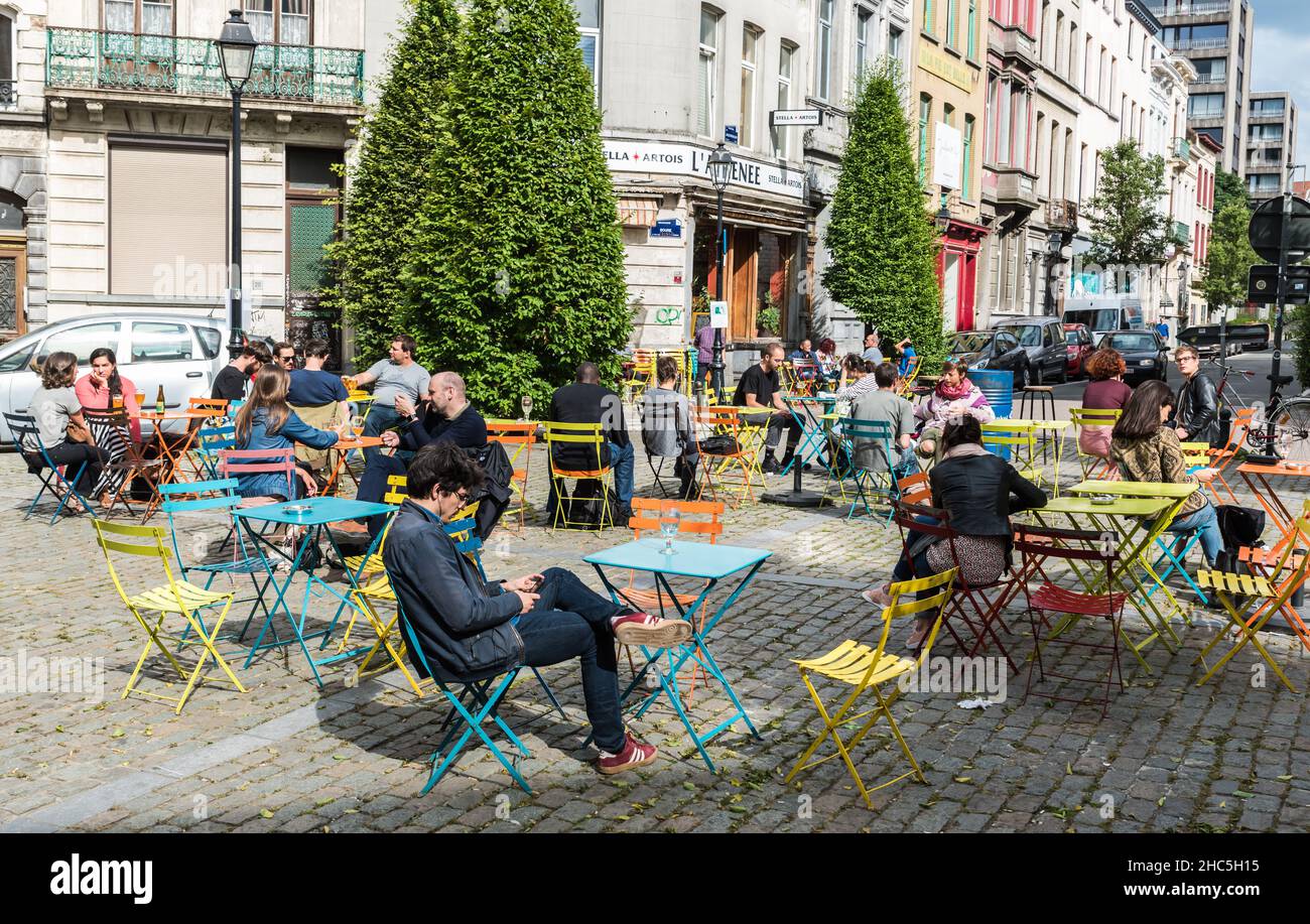 Ixelles, Bruxelles / Belgio - 06 16 2018: Persone sedute su una vivace terrazza, leggere e bere all'ombra della chiesa Foto Stock