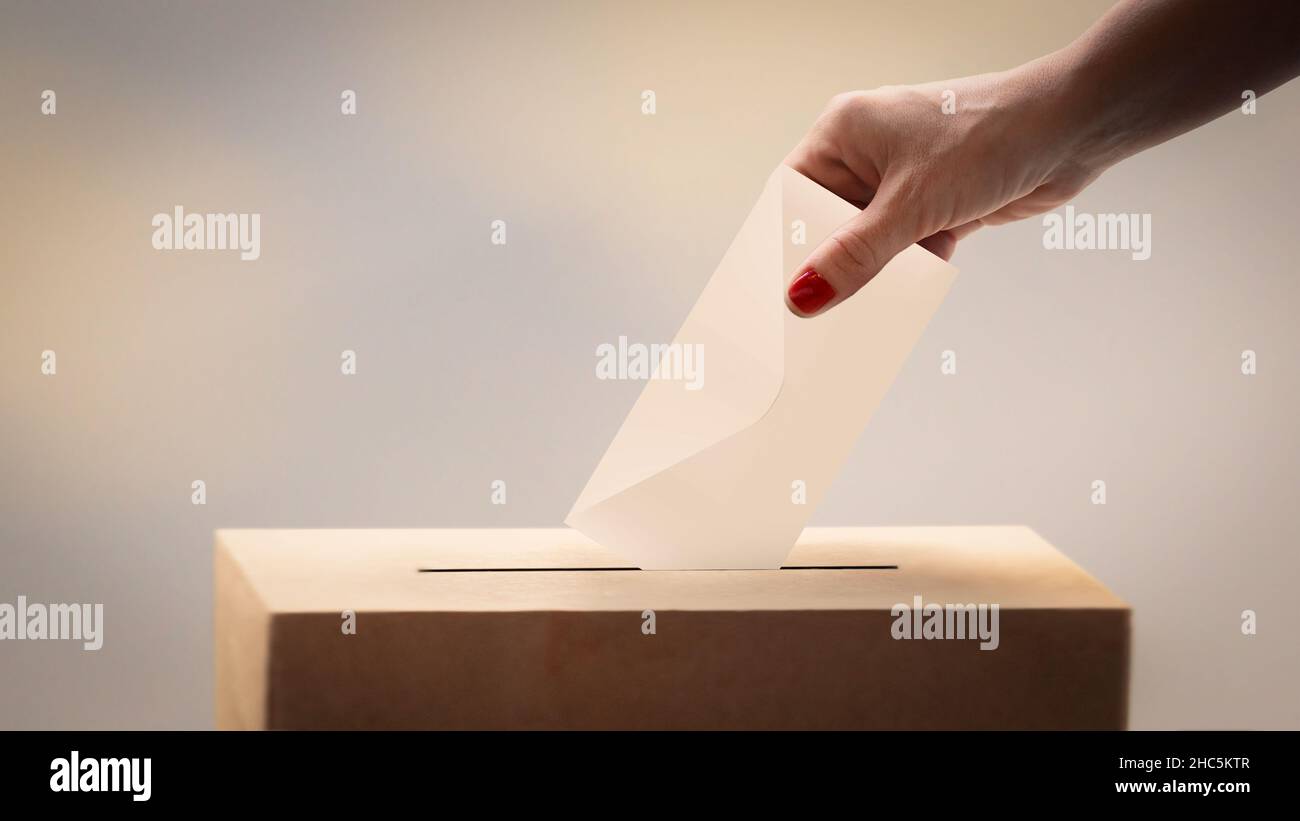 concetto di scelta. Voter femminile che getta il suo ballottaggio alla scatola di voto Foto Stock