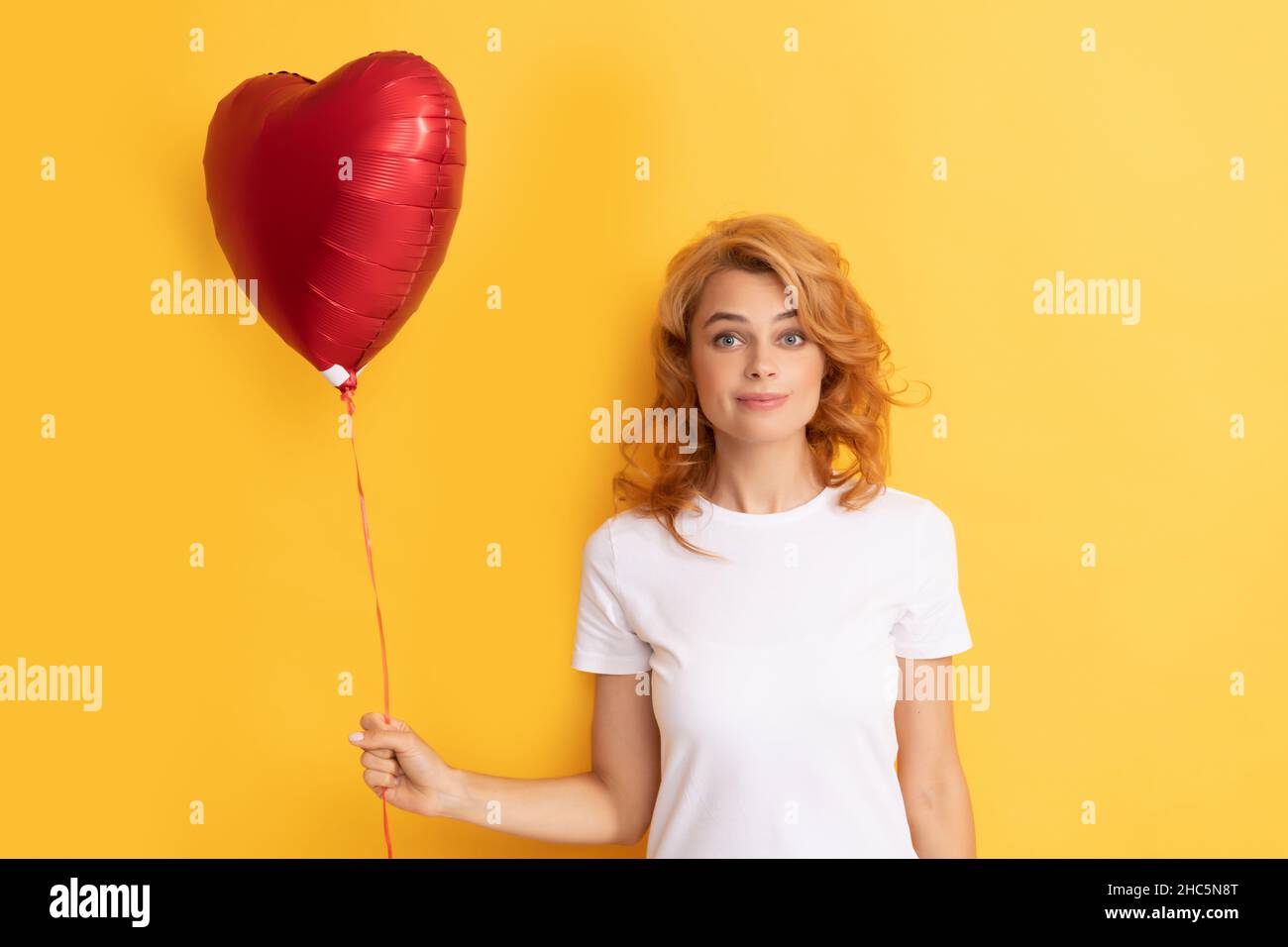 stupito redhead ragazza con cuore di balloon amore. carità e donazione Foto Stock