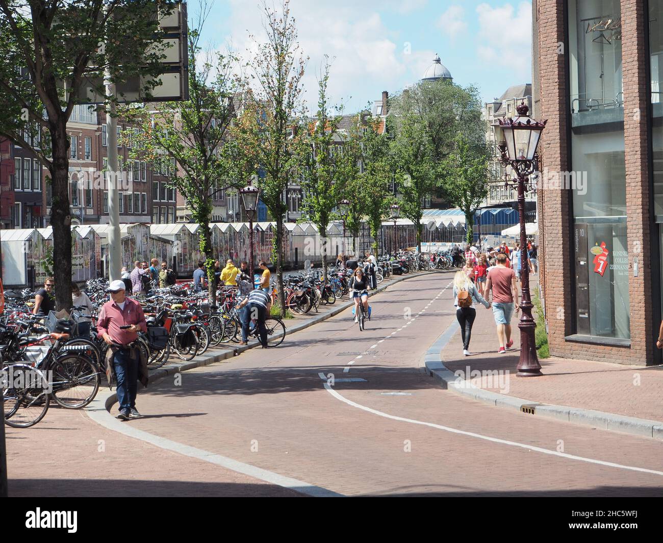 Strada trafficata centrale di Amsterdam con biciclette parcheggiate Foto Stock