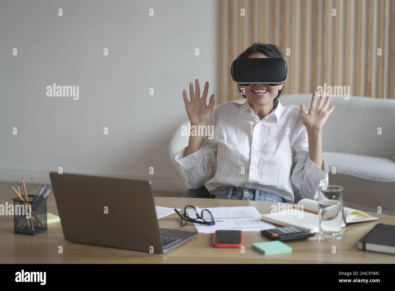 Donna d'affari entusiasta che indossa occhiali per realtà virtuale mentre lavora in ufficio Foto Stock