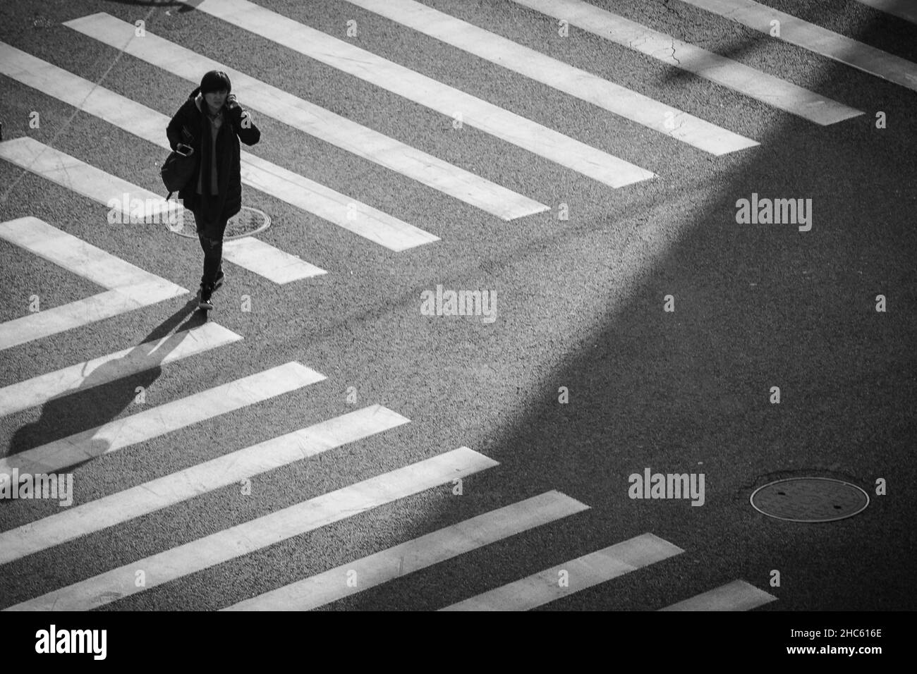 Una donna con una grande borsa si erge proprio all'angolo dove 2 incroci zebra si incontrano in questa foto da un edificio alto, Weining Road, Shanghai, Cina Foto Stock