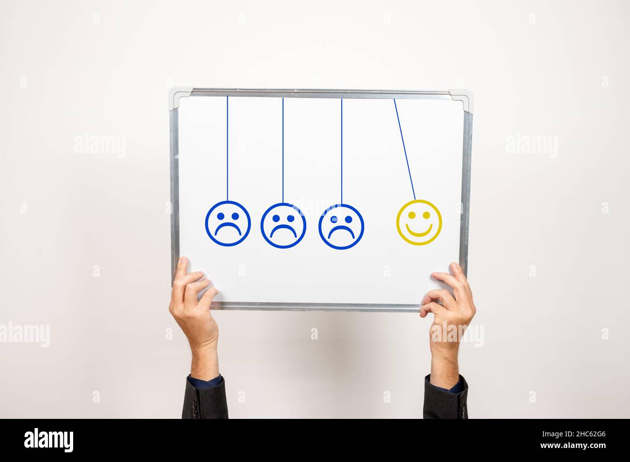 NewtonÂ's culla stile 3 blu accigliato emoji con uno sorridente emoji tenuto da una persona dal basso Foto Stock