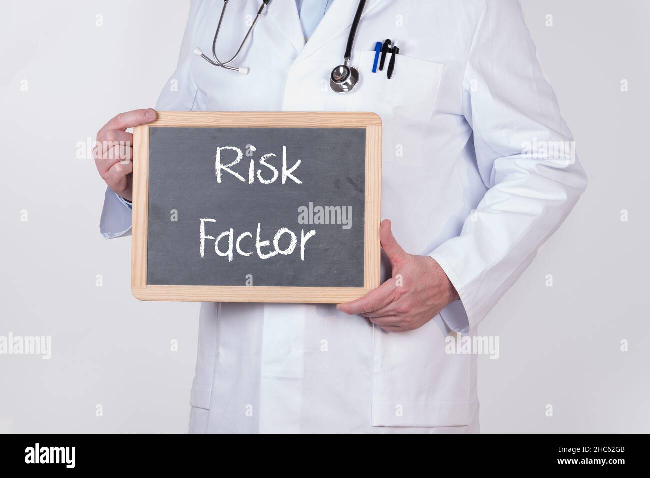 Medico che tiene una lavagna con il testo del fattore di rischio Foto Stock