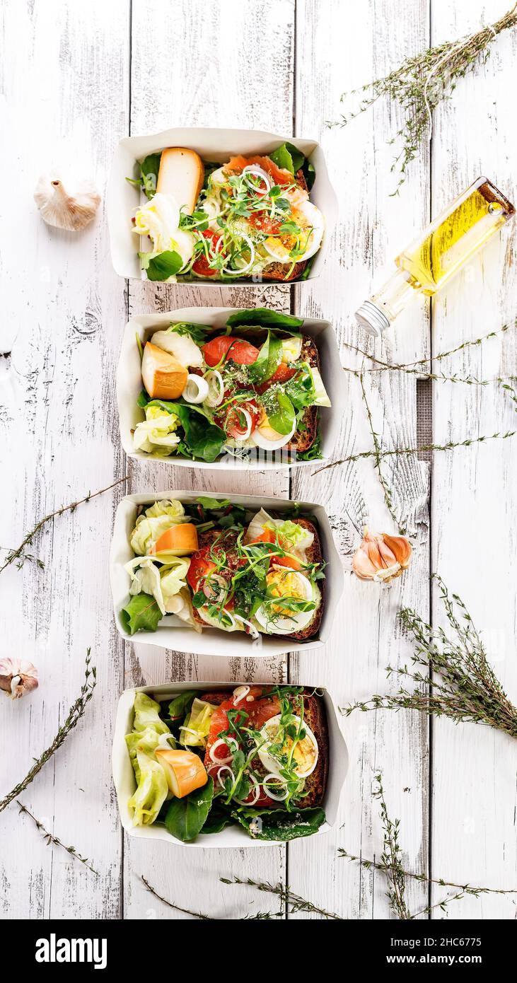 Pranzo delizioso e salutare con filetto di salmone in una scatola di carte. Insalata con salmone affumicato, formaggio, uova, cipolla e verdure. Dieta di pesce Foto Stock