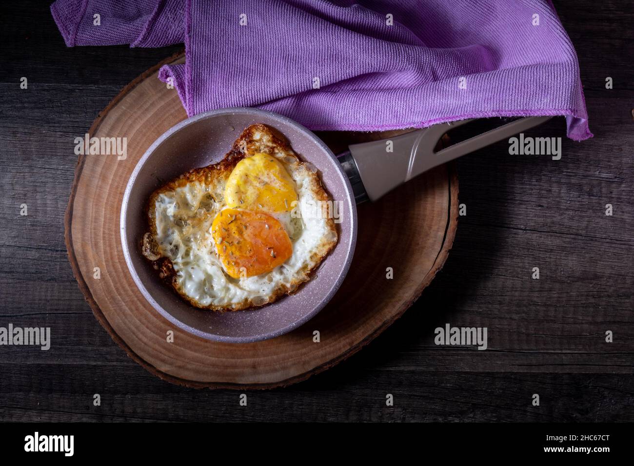 le uova, sempre nella padella, sono riposte su un tagliere di legno Foto Stock