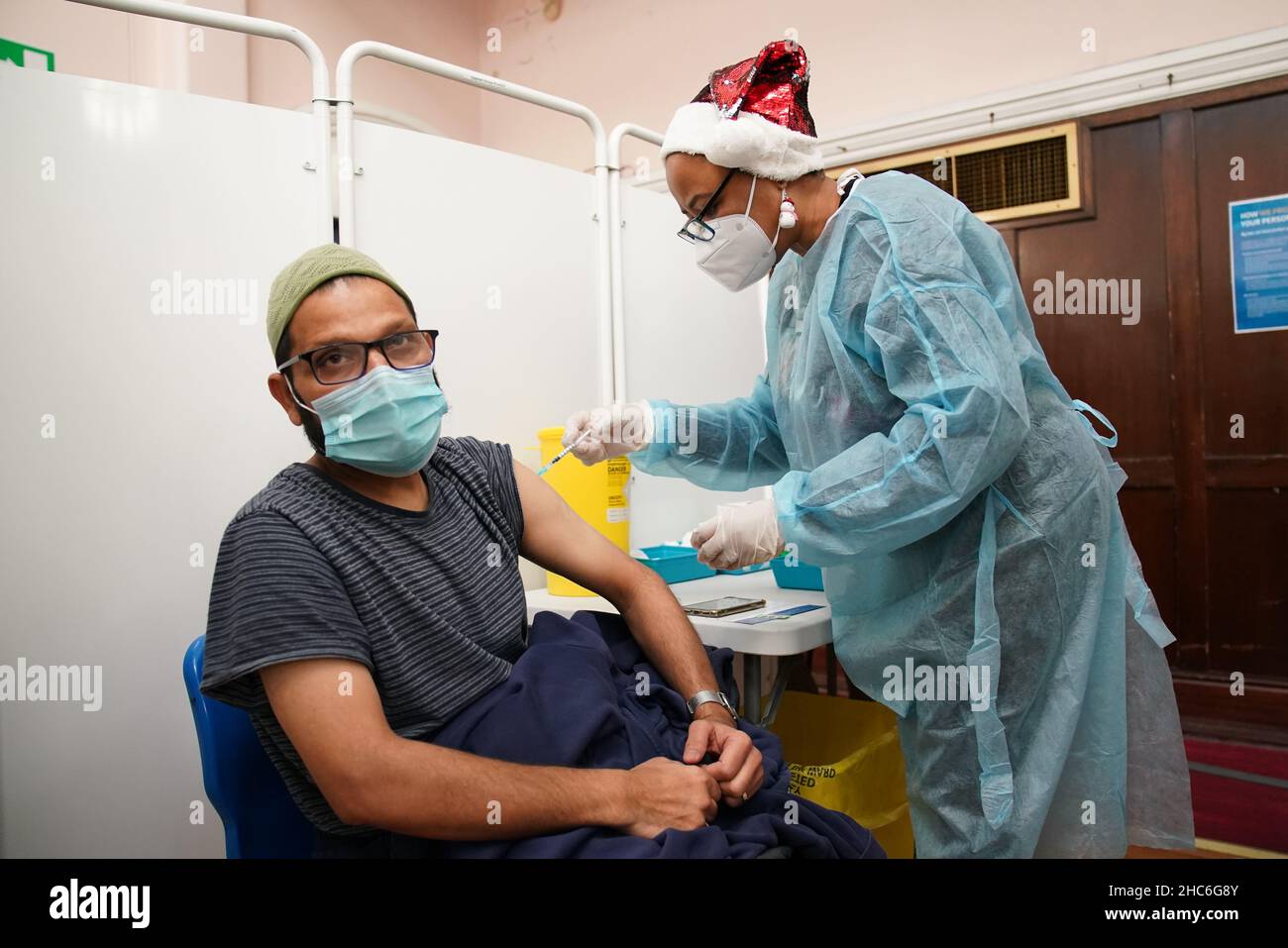 Un uomo riceve un'iniezione di richiamo della vaccinazione 'Jingle Jab' di Covid al Municipio di Redbridge, ad Ilford, Essex, mentre il programma di richiamo del coronavirus continua in tutto il Regno Unito il giorno di Natale. Data foto: Sabato 25 dicembre 2021. Foto Stock
