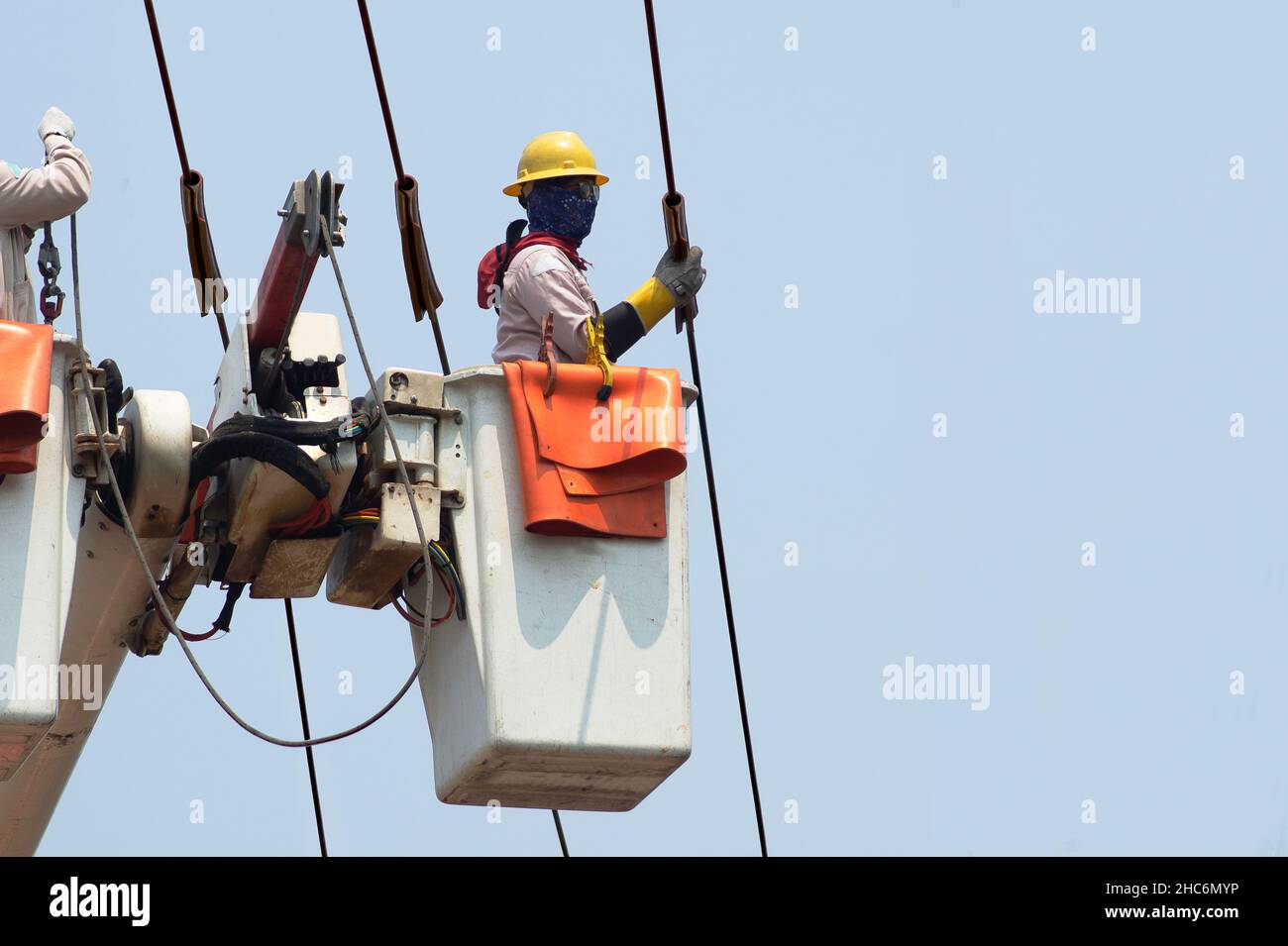 Gli elettricisti lavorano insieme sulla funivia elettrica e sul polo elettrico. Per mantenere il sistema di distribuzione ad alta e bassa tensione. Indossano un casco w Foto Stock