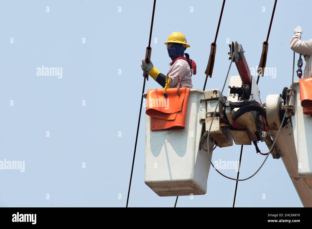 Gli elettricisti lavorano insieme sulla funivia elettrica e sul polo elettrico. Per mantenere il sistema di distribuzione ad alta e bassa tensione. Indossano un casco w Foto Stock