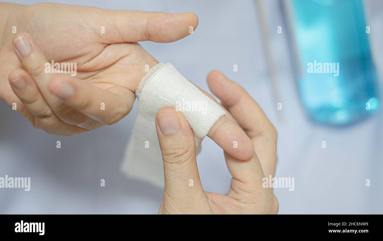 Le donne che usano la bendatura intorno alla sutura del dito per uccidere i germi. Foto Stock