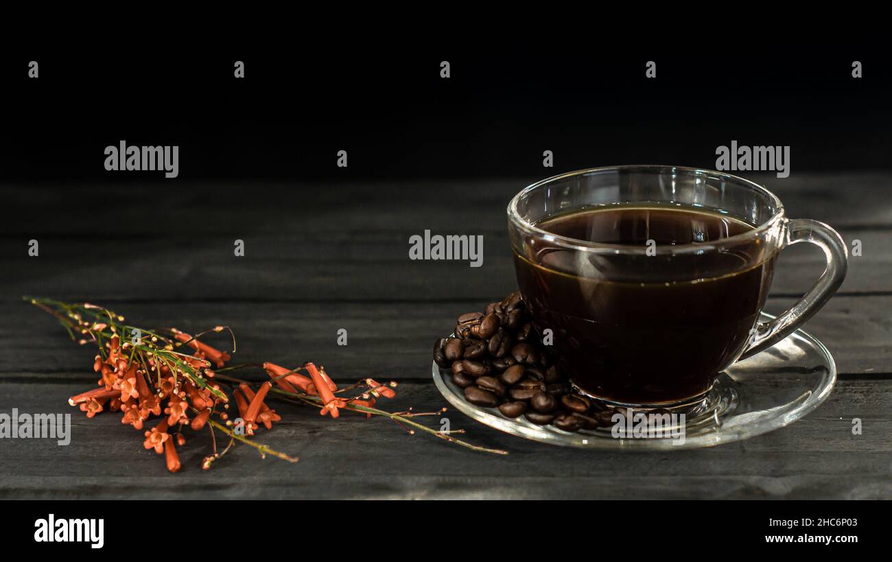 Caffè caldo in una tazza di caffè e chicchi di caffè torrefatti con pavimento in legno scuro. E c'è uno spazio per le copie. Foto Stock