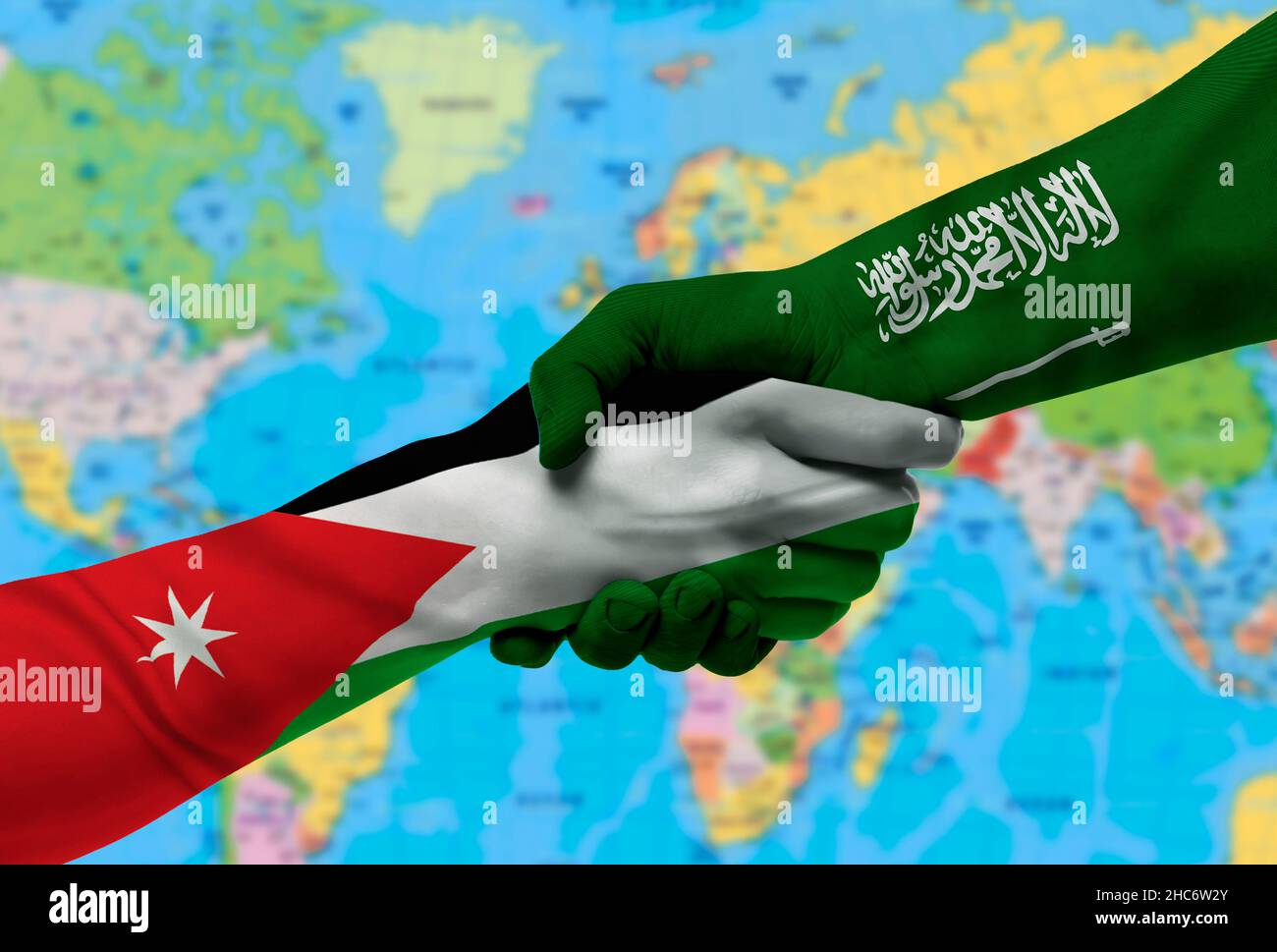 Handshake tra l'Arabia Saudita e la Giordania bandiere dipinte su mani.con sfondo della mappa del mondo Foto Stock