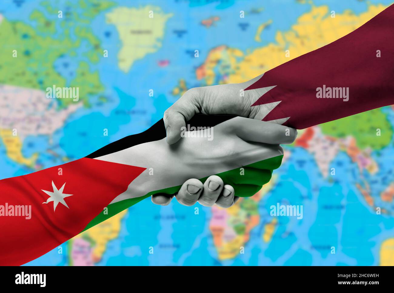 Handshake tra Qatar e Jordan bandiere dipinte su hands.with sfondo della mappa del mondo Foto Stock