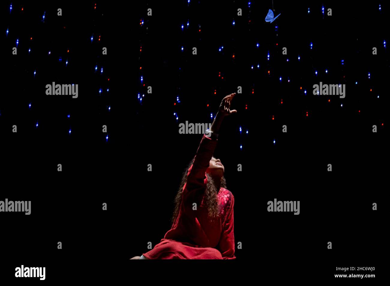 Ragazza in un abito rosso che raggiunge le stelle nel buio in Alif Pavilion of Expo 2020 a Dubai Foto Stock