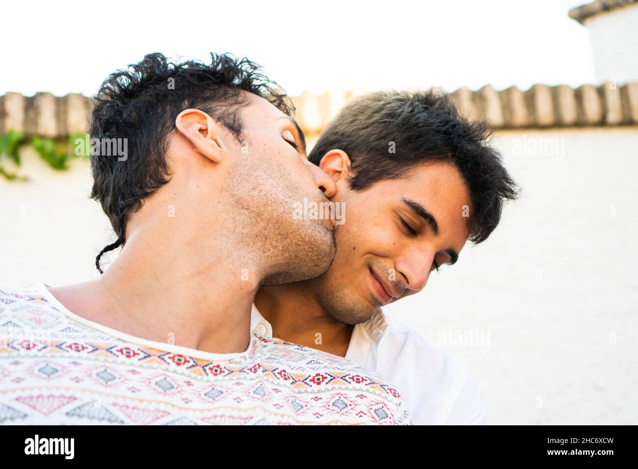 Il ragazzo bacia il suo compagno nella guancia. Giovane coppia gay innamorata. Ritratto romantico in estate Foto Stock