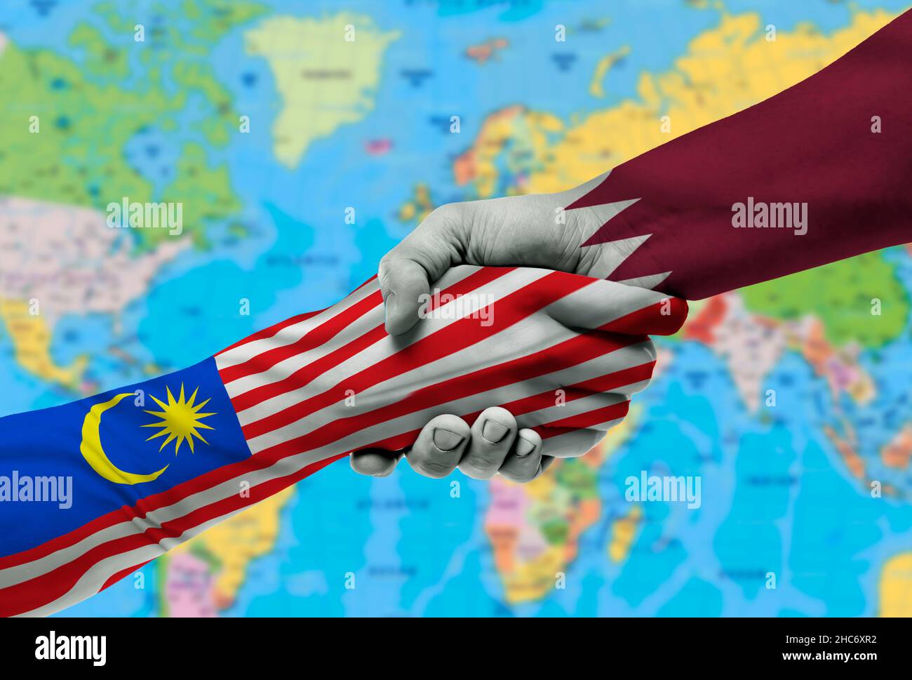 Bandiere paesi del Qatar e della Malesia, cooperazione di handshake, associazione e amicizia o sport competition.with sfondo della mappa del mondo Foto Stock