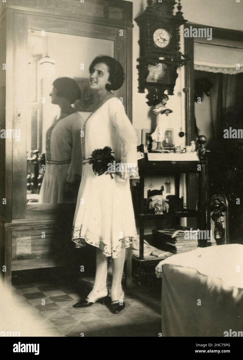 Donna vestita di bianco nella sua camera da letto, Italia 1920s Foto Stock