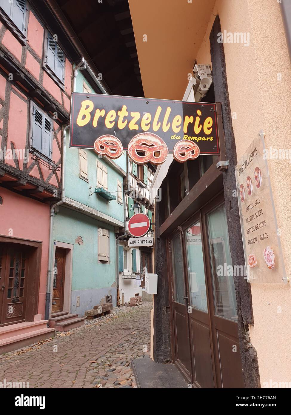 Vecchio, vicolo stretto e fast food segno nella città di Eguisheim, Alsazia, Francia Foto Stock